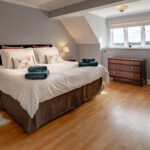 double bed in large room with sloping ceiling and wood floor
