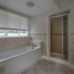 bath in peach coloured bathroom and shower cubicle with window